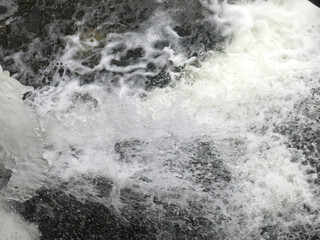 water gushes in a stormy stream in winter, there is ice around