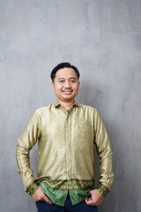 Smiling adult Asian man wearing traditional batik with a casual pose - Indonesian culture