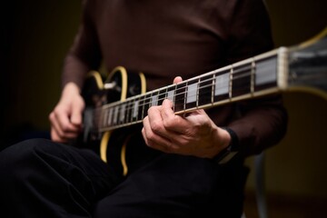 Obraz premium Close Up of Hands Playing a Guitar in a Warm and Cozy Setting Filled with Music and Art
