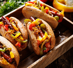 Sausage sandwiches with colorful peppers and onion, focus on the middle, close up view