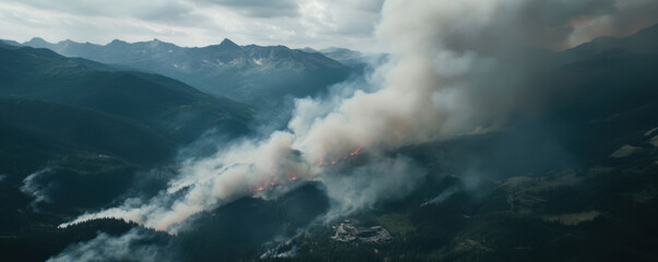 Fototapeta premium Aerial view of wildfire threatening mountainous area, with smoke billowing and flames visible in forest. scene captures intensity and danger of fire