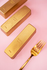 dessert in the form of a gold bar with fork isolated on the pink background
