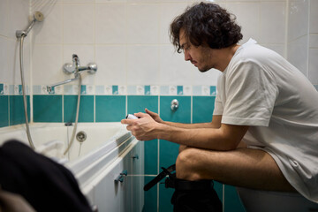 A Man Engaged in a Leisurely Activity While Relaxing in a Comfortable Bathroom Setting