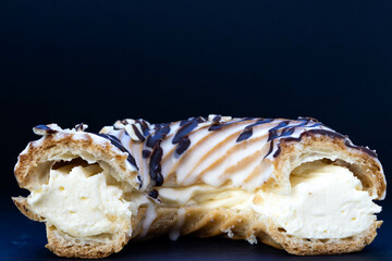 Close-up of a ring-shaped eclair cut in half on a black background.
