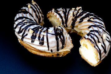 Close-up of a ring-shaped eclair cut in half on a black background.