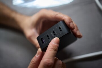 Detailed closeup image of a hand firmly holding a USB hub that features multiple ports