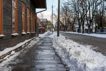 Small town street in winter in Latvia with piles of ice and snow