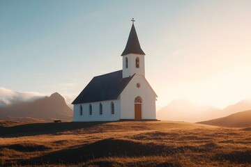 Serene sunset view of a white church on a grassy hill against a mountain backdrop.