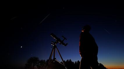 Amateur astronomer looking at the evening skies, observing planets, Moon and stars.