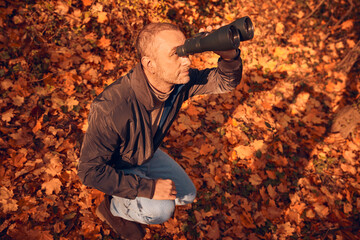 Amateur birdwatcher observing birds and other animals in nature with binoculars.