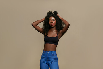 Smiling African American woman with natural long curly hair , wearing a black crop top and blue...