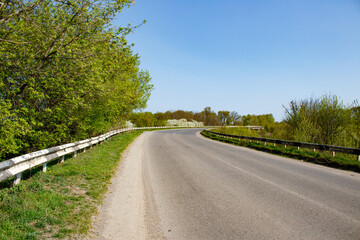 A country road with a white fence on the side of it