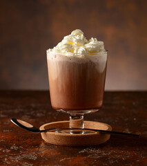 Hot chocolate with whipped cream in a glass mug.