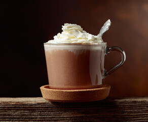 Hot chocolate with whipped cream in a glass mug.