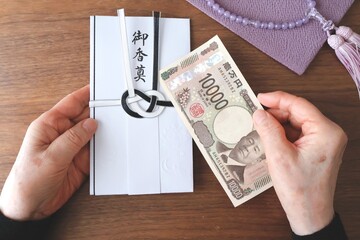 香典袋とお札を持つシニア女性の手