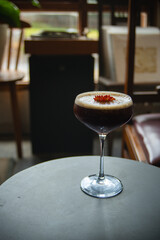 Iced cold brew coffee with lemon and infused with floral essence, served using transparent coupe glass, in an indoor retro cafe environment