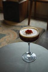 Iced cold brew coffee with lemon and infused with floral essence, served using transparent coupe glass, in an indoor retro cafe environment