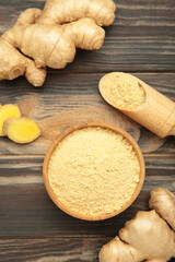 Fototapeta premium Ginger powder on white plate with fresh ginger root on brown wooden background. Top view