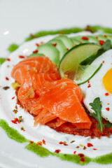 Poached eggs on top of smashed avocado on sourdough toast with smoked salmon. Healthy breakfast with plate on table. Top view. Copy space to right 