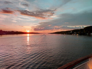 Obraz premium Golden sunset over the river, view from the motorboat on the calm water surface and houses on the shore, beautiful evening panorama
