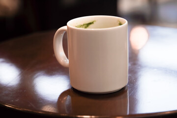 Blank white mockup ceramic mug for tea and coffee on wooden table.