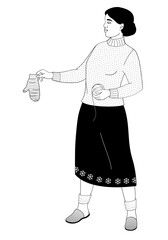 African American woman stands and holds a knitted mitten and a ball of thread in her hands