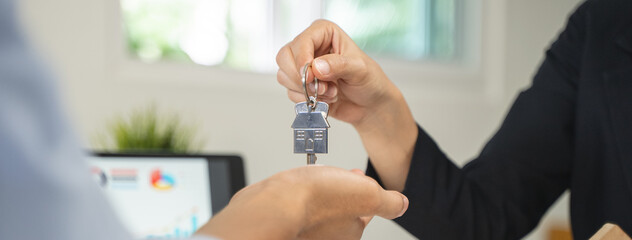 Realtor agent giving a key of apartment to new owner after signed lease agreement.