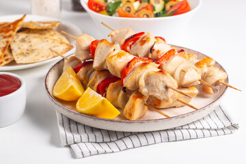 Delicious grilled chicken skewers with capsicum, lemon, salad and ketchup on a plate over the table. Chicken kebab. Healthy food concept.