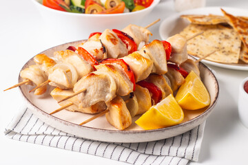 Delicious grilled chicken skewers with capsicum, lemon, salad and ketchup on a plate over the table. Chicken kebab. Healthy food concept.