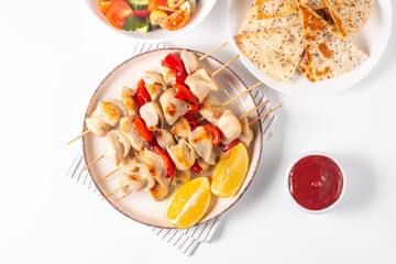 Delicious grilled chicken skewers with capsicum, lemon, salad and ketchup on a plate over the table. Chicken kebab. Healthy food concept.