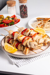 Delicious grilled chicken skewers with capsicum, lemon, salad and ketchup on a plate over the table. Chicken kebab. Healthy food concept.