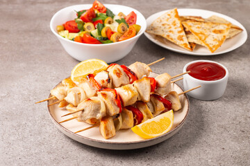Delicious grilled chicken skewers with capsicum, lemon, salad and ketchup on a plate over the table. Chicken kebab. Healthy food concept.