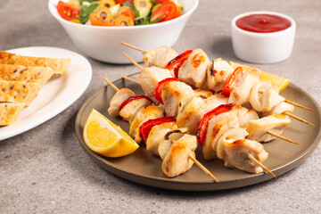 Delicious grilled chicken skewers with capsicum, lemon, salad and ketchup on a plate over the table. Chicken kebab. Healthy food concept.