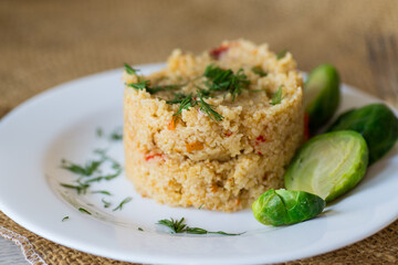 homemade cooked bulgur with Brussel sprouts in a plate, on a wooden table