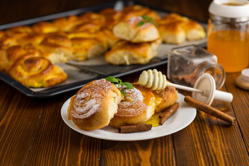 Pastries. Sweet buns with cottage cheese filling and honey in a plate on a wooden table