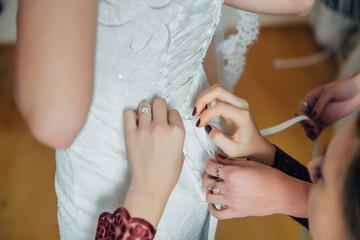 A woman is getting her dress altered by another woman. The dress is white and has lace on it. The two women are working together to make sure the dress fits perfectly
