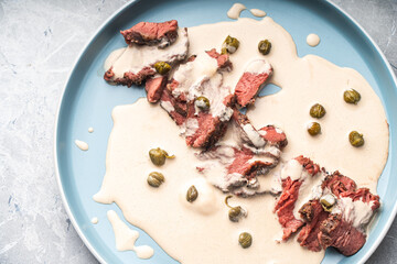 Vitello tonnato a traditional Italian dish of meat with tuna and anchovy cream sauce. Thin slices of beef in vitello tonnato sauce.Top view, close-up. High quality photo