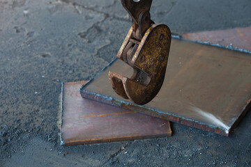 Clamp for lifting sheet metal with a crane. Clamp for moving metal plates with thick metal plates lying next to them