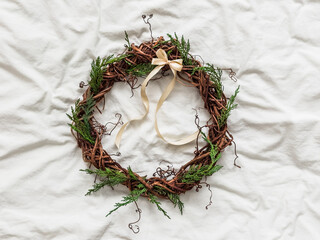 Homemade vine wreath decorated with ribbon for interior decoration on a light background, top view