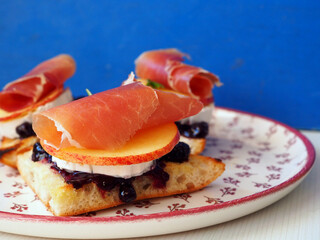 Spanish Tapas with Goat Cheese, Blueberry Jam, Serrano Ham, and Apple Slice on Artisan Bread