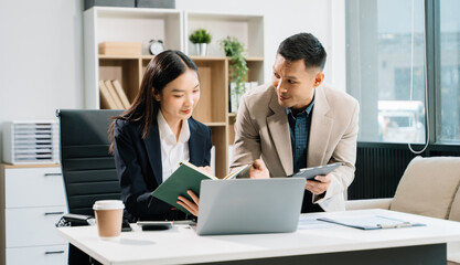 Two business workers talking on the smartphone and using laptop at the office..