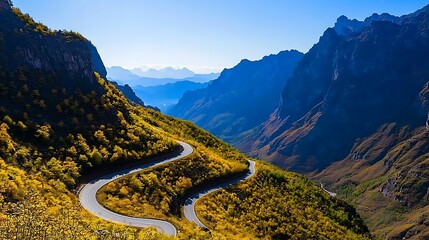 Scenic winding road through vibrant autumn mountains with distant peaks and clear sky