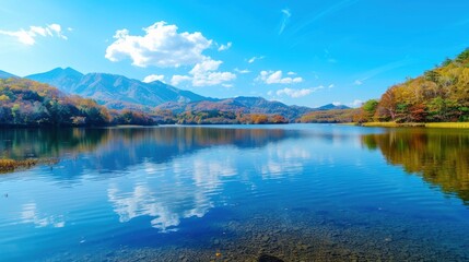 Fototapeta premium Colorful Autumn Foliage Reflected on Serene Lake with Mountain Backdrop, Gentle Sunlight Casting Shadows, Nature's Harmony