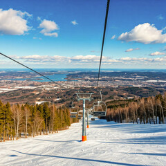 Scenic view of a snowy mountain slope with a ski lift, overlooking a city and serene winter landscape, including distant forests and a tranquil lake under a vivid blue sky.
