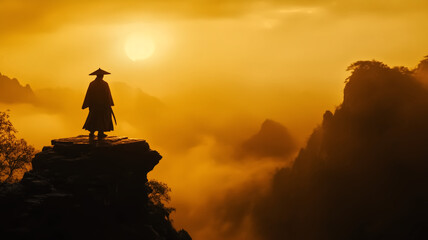 Fototapeta premium lone figure stands on cliff, silhouetted against dramatic golden sunset, overlooking misty mountains. scene evokes sense of solitude and contemplation
