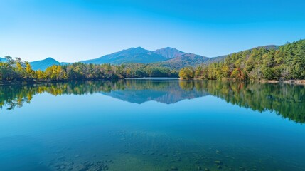 Fototapeta premium Autumn Scenery: Serene Lake with Reflective Mountains, Clear Water, and Surrounding Forests in Natural Lighting