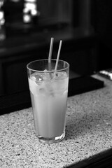 a glass with a drink is on the bar counter, drinking sticks are visible, a yellow drink in the bar glass of milk on the table