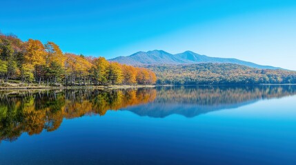 Naklejka premium Serene Autumn Landscape at Lake with Mountain Backdrop, Colorful Trees Reflecting on Calm Water Surface