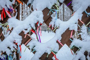 A close-up of a wooden lattice adorned with vibrant ribbons in various colors, partially covered by...