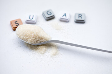White granulated sugar in a spoon with letter tiles spelling 